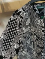 نمای نزدیک جواهردوزی گل و برگ روی پارچه مشکی