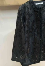 نمای نزدیک از گل‌های ملیله‌دوزی شده با رنگ سفید و طلایی روی مانتو