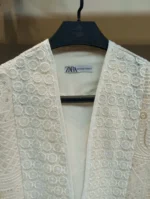 نمای نزدیک خرجکار دست‌دوز روی پارچه دانتل کرم